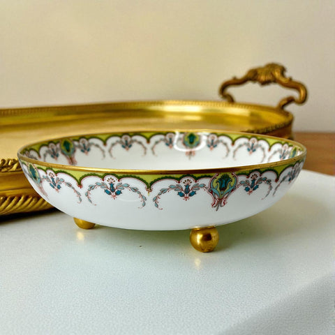 Antique Haviland Limoges France porcelain serving bowl with three gold spherical feet, ornate rim featuring floral and scroll motifs in blue, green, red, and gold; white base with maker’s marks “Haviland France” and “Haviland & Co Limoges”; very good vintage condition with one small factory flaw in center