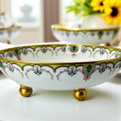 Antique Haviland Limoges France porcelain serving bowl with three gold spherical feet, ornate rim featuring floral and scroll motifs in blue, green, red, and gold; white base with maker’s marks “Haviland France” and “Haviland & Co Limoges”; very good vintage condition with one small factory flaw in center