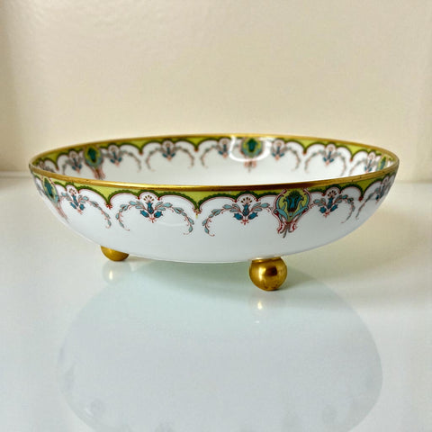 Antique Haviland Limoges France porcelain serving bowl with three gold spherical feet, ornate rim featuring floral and scroll motifs in blue, green, red, and gold; white base with maker’s marks “Haviland France” and “Haviland & Co Limoges”; very good vintage condition with one small factory flaw in center