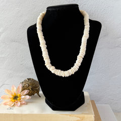 Vintage 1970s Hawaiian puka shell necklace made of natural white‑cream shells, shown coiled on a neutral background.