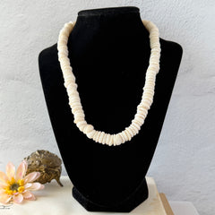 Vintage 1970s Hawaiian puka shell necklace made of natural white‑cream shells, shown coiled on a neutral background.