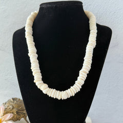Vintage 1970s Hawaiian puka shell necklace made of natural white‑cream shells, shown coiled on a neutral background.