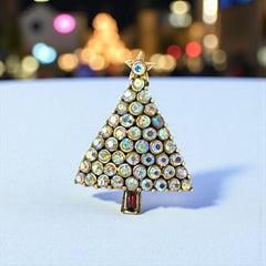 Vintage Hollycraft Christmas tree brooch with clear Aurora Borealis rhinestones in a gold-tone setting, featuring a gold star at the top and a red rhinestone base. Signed on the reverse and measuring approximately 1 3/8 inches tall by 1 inch wide.