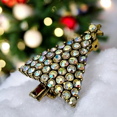 Vintage Hollycraft Christmas tree brooch with clear Aurora Borealis rhinestones in a gold-tone setting, featuring a gold star at the top and a red rhinestone base. Signed on the reverse and measuring approximately 1 3/8 inches tall by 1 inch wide.