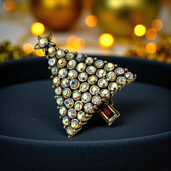 Vintage Hollycraft Christmas tree brooch with clear Aurora Borealis rhinestones in a gold-tone setting, featuring a gold star at the top and a red rhinestone base. Signed on the reverse and measuring approximately 1 3/8 inches tall by 1 inch wide.