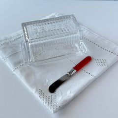 Vintage clear glass butter dish with raised “Beurre” lettering visible through the lid and ribbed radiating base.