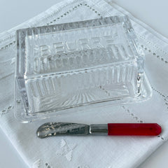 Vintage clear glass butter dish with raised “Beurre” lettering visible through the lid and ribbed radiating base.