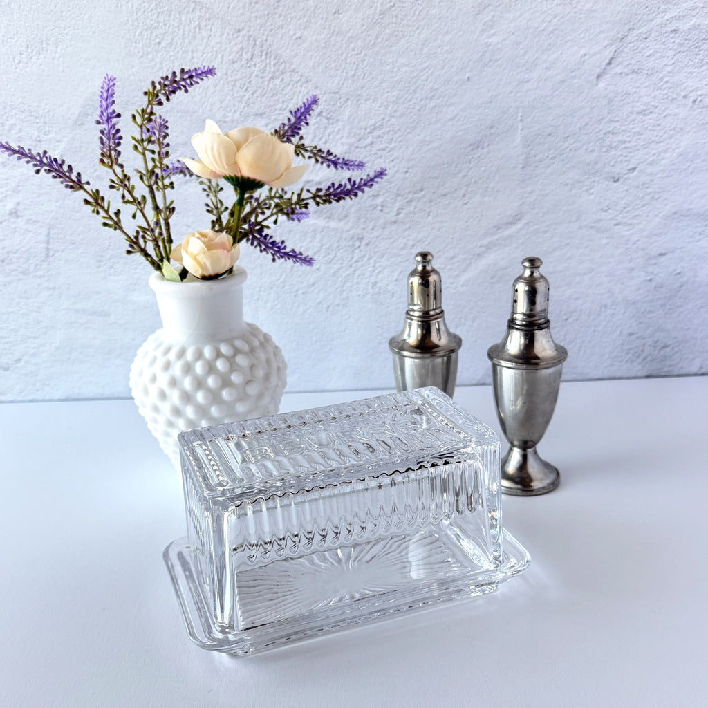 Vintage clear glass butter dish with raised “Beurre” lettering visible through the lid and ribbed radiating base.