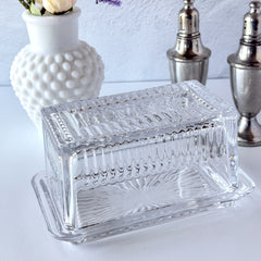 Vintage clear glass butter dish with raised “Beurre” lettering visible through the lid and ribbed radiating base.