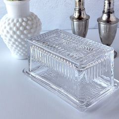 Vintage clear glass butter dish with raised “Beurre” lettering visible through the lid and ribbed radiating base.