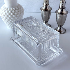 Vintage clear glass butter dish with raised “Beurre” lettering visible through the lid and ribbed radiating base.