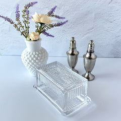 Vintage clear glass butter dish with raised “Beurre” lettering visible through the lid and ribbed radiating base.