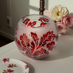 Vintage Illuminations frosted glass candle holder with etched red Spanish lace leaf pattern, rose bowl shape, softly glowing surface ideal for holiday decor or cozy ambiance.