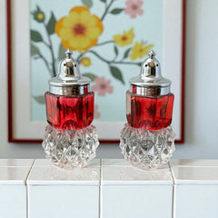 Pair of vintage Indiana Glass salt and pepper shakers featuring clear diamond point bases, paneled ruby red flash bands, and chrome-plated screw-on lids marked Made in Hong Kong. Mid-century design in excellent vintage condition.