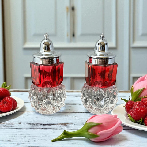 Pair of vintage Indiana Glass salt and pepper shakers featuring clear diamond point bases, paneled ruby red flash bands, and chrome-plated screw-on lids marked Made in Hong Kong. Mid-century design in excellent vintage condition.