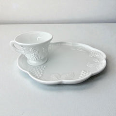  Vintage Indiana Glass Colony Harvest Grape milk glass snack plate and cup set from the 1960s, featuring embossed grapevine motifs and glossy white finish.
