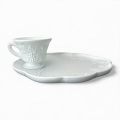  Vintage Indiana Glass Colony Harvest Grape milk glass snack plate and cup set from the 1960s, featuring embossed grapevine motifs and glossy white finish.
