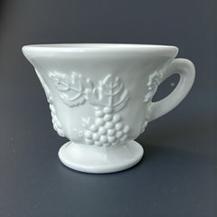  Vintage Indiana Glass Colony Harvest Grape milk glass snack plate and cup set from the 1960s, featuring embossed grapevine motifs and glossy white finish.
