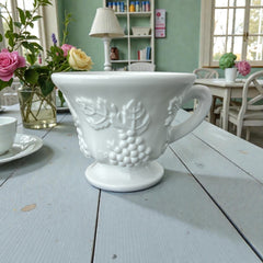  Vintage Indiana Glass Colony Harvest Grape milk glass snack plate and cup set from the 1960s, featuring embossed grapevine motifs and glossy white finish.
