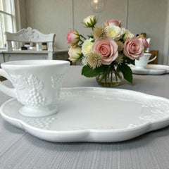  Vintage Indiana Glass Colony Harvest Grape milk glass snack plate and cup set from the 1960s, featuring embossed grapevine motifs and glossy white finish.
