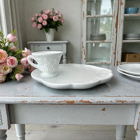  Vintage Indiana Glass Colony Harvest Grape milk glass snack plate and cup set from the 1960s, featuring embossed grapevine motifs and glossy white finish.

