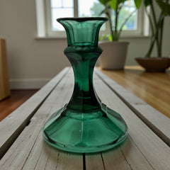 Pair of vintage Indiana Glass green candlestick holders with hexagonal bases, shown on a white surface. The emerald green glass catches the light, highlighting their faceted mid-century design and tapered silhouette. Ideal for holiday styling or eco-conscious vintage decor.