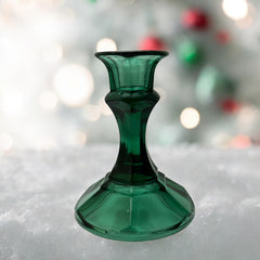 Pair of vintage Indiana Glass green candlestick holders with hexagonal bases, shown on a white surface. The emerald green glass catches the light, highlighting their faceted mid-century design and tapered silhouette. Ideal for holiday styling or eco-conscious vintage decor.