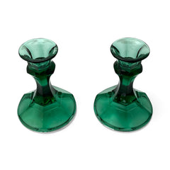 Pair of vintage Indiana Glass green candlestick holders with hexagonal bases, shown on a white surface. The emerald green glass catches the light, highlighting their faceted mid-century design and tapered silhouette. Ideal for holiday styling or eco-conscious vintage decor.
