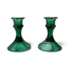 Pair of vintage Indiana Glass green candlestick holders with hexagonal bases, shown on a white surface. The emerald green glass catches the light, highlighting their faceted mid-century design and tapered silhouette. Ideal for holiday styling or eco-conscious vintage decor.