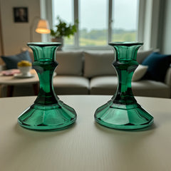Pair of vintage Indiana Glass green candlestick holders with hexagonal bases, shown on a white surface. The emerald green glass catches the light, highlighting their faceted mid-century design and tapered silhouette. Ideal for holiday styling or eco-conscious vintage decor.