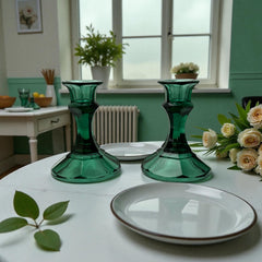 Pair of vintage Indiana Glass green candlestick holders with hexagonal bases, shown on a white surface. The emerald green glass catches the light, highlighting their faceted mid-century design and tapered silhouette. Ideal for holiday styling or eco-conscious vintage decor.