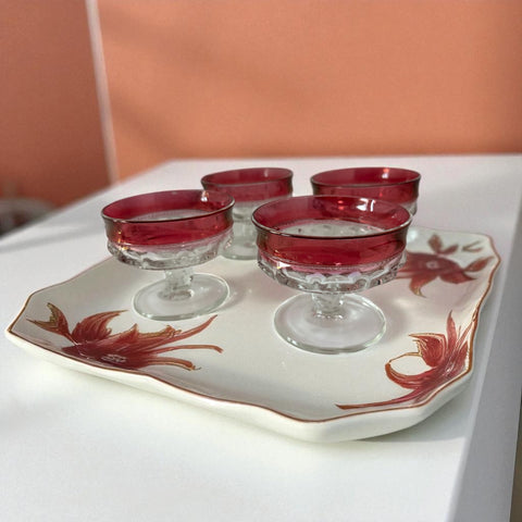 Set of vintage Indiana Glass cranberry sherbet glasses with thumbprint detailing, styled with soft lighting and floral accents to highlight their color, texture, and collectible charm.