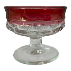 Set of vintage Indiana Glass cranberry sherbet glasses with thumbprint detailing, styled with soft lighting and floral accents to highlight their color, texture, and collectible charm.