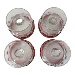 Set of vintage Indiana Glass cranberry sherbet glasses with thumbprint detailing, styled with soft lighting and floral accents to highlight their color, texture, and collectible charm.