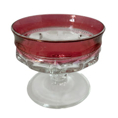 Set of vintage Indiana Glass cranberry sherbet glasses with thumbprint detailing, styled with soft lighting and floral accents to highlight their color, texture, and collectible charm.