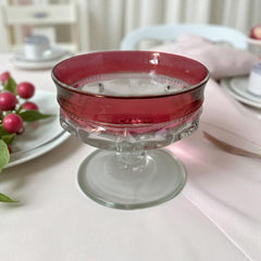 Set of vintage Indiana Glass cranberry sherbet glasses with thumbprint detailing, styled with soft lighting and floral accents to highlight their color, texture, and collectible charm.