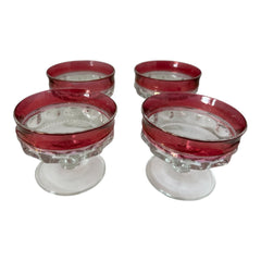 Set of vintage Indiana Glass cranberry sherbet glasses with thumbprint detailing, styled with soft lighting and floral accents to highlight their color, texture, and collectible charm.