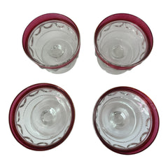 Set of vintage Indiana Glass cranberry sherbet glasses with thumbprint detailing, styled with soft lighting and floral accents to highlight their color, texture, and collectible charm.