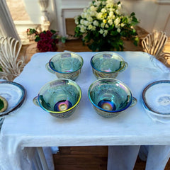 Set of four vintage Indiana Glass punch or tea cups in Princess Blue Harvest Grape pattern, made in the early 1970s; iridescent blue glass with embossed grape and leaf motifs, each cup approx. 2⅜" tall and 3⅜" in diameter, with 4¼" width including handle; excellent vintage condition with vibrant multicolor sheen.