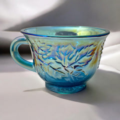 Set of four vintage Indiana Glass punch or tea cups in Princess Blue Harvest Grape pattern, made in the early 1970s; iridescent blue glass with embossed grape and leaf motifs, each cup approx. 2⅜" tall and 3⅜" in diameter, with 4¼" width including handle; excellent vintage condition with vibrant multicolor sheen.