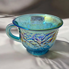 Set of four vintage Indiana Glass punch or tea cups in Princess Blue Harvest Grape pattern, made in the early 1970s; iridescent blue glass with embossed grape and leaf motifs, each cup approx. 2⅜" tall and 3⅜" in diameter, with 4¼" width including handle; excellent vintage condition with vibrant multicolor sheen.