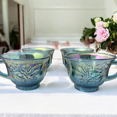 Set of four vintage Indiana Glass punch or tea cups in Princess Blue Harvest Grape pattern, made in the early 1970s; iridescent blue glass with embossed grape and leaf motifs, each cup approx. 2⅜" tall and 3⅜" in diameter, with 4¼" width including handle; excellent vintage condition with vibrant multicolor sheen.