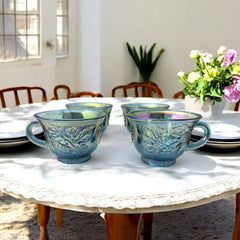 Set of four vintage Indiana Glass punch or tea cups in Princess Blue Harvest Grape pattern, made in the early 1970s; iridescent blue glass with embossed grape and leaf motifs, each cup approx. 2⅜" tall and 3⅜" in diameter, with 4¼" width including handle; excellent vintage condition with vibrant multicolor sheen.
