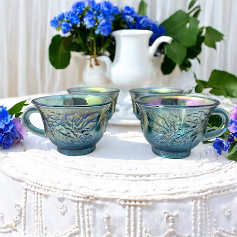 Set of four vintage Indiana Glass punch or tea cups in Princess Blue Harvest Grape pattern, made in the early 1970s; iridescent blue glass with embossed grape and leaf motifs, each cup approx. 2⅜" tall and 3⅜" in diameter, with 4¼" width including handle; excellent vintage condition with vibrant multicolor sheen.