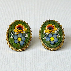 Vintage oval Italian micro‑mosaic clip‑on earrings with yellow and blue floral designs on a green background, framed in a gold‑tone twisted rope border. The mosaic is intact and detailed, with light wear visible on the backs.