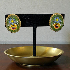 Vintage oval Italian micro‑mosaic clip‑on earrings with yellow and blue floral designs on a green background, framed in a gold‑tone twisted rope border. The mosaic is intact and detailed, with light wear visible on the backs.