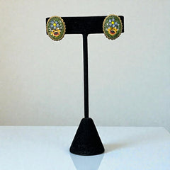 Vintage oval Italian micro‑mosaic clip‑on earrings with yellow and blue floral designs on a green background, framed in a gold‑tone twisted rope border. The mosaic is intact and detailed, with light wear visible on the backs.