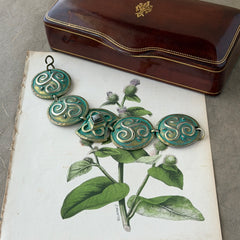 Close‑up of a vintage Ivar Hyden Celtic bracelet with round brass‑tone links, green patina, and a square hematite cabochon centerpiece.