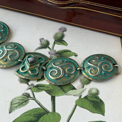 Close‑up of a vintage Ivar Hyden Celtic bracelet with round brass‑tone links, green patina, and a square hematite cabochon centerpiece.
