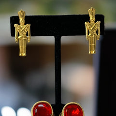 Gold tone vintage nutcracker earrings by JJ, featuring detailed toy soldier figures with tall hats and crossed arms; signed on the back with copyright symbol.